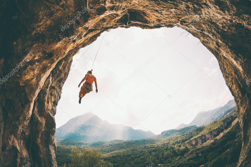 Rock climber hanging on a rope. A woman climbs a rock in the shape of an arch. The girl climbs in the cave. Climbing rope for belaying. Rock climbing in Turkey .