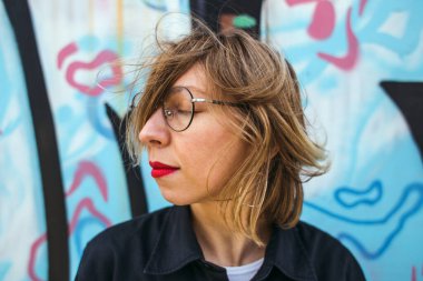 Gözlüklü sarışının portresi. Bir kadın şehirde dolaşıyor. Gülümseyen kız. Kırmızı rujlu dudaklar..