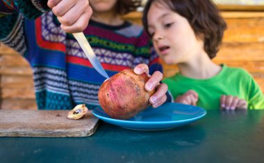 Mavi bir tabakta olgun, sulu bir nar. Çocuk, annesinin narı kesişini izliyor. Sağlıklı meyve ikiye bölünür..