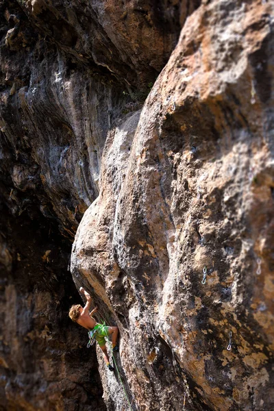 一位年轻的运动员爬上岩石 一位登山者在自然的地形上训练 一位男子训练力量和耐力 一位儿童和青少年攀岩 — 图库照片