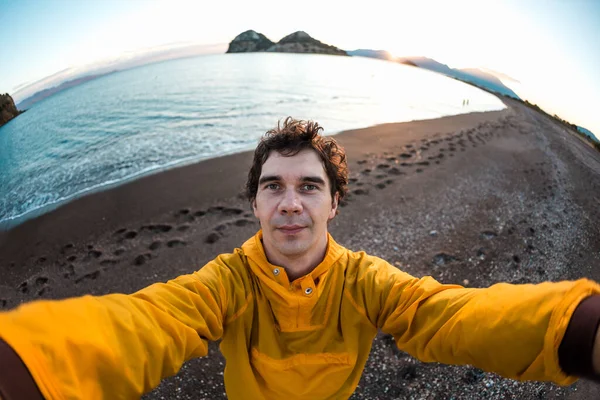 Sarı Ceketli Genç Adam Gün Batımında Deniz Kıyısında Selfie Çekiyor — Stok fotoğraf