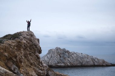 Sırt çantalı kız deniz kıyısındaki bir dağda duruyor. Gezgin, dağda durarak denize bakıyor. Türkiye 'ye gitmek. özgürlük ve mutluluk.