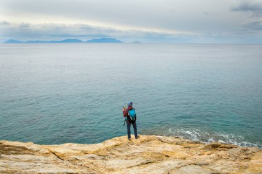 Sırt çantalı kız deniz kıyısındaki bir dağda duruyor. Gezgin, dağda durarak denize bakıyor. Türkiye 'ye gitmek. özgürlük ve mutluluk.