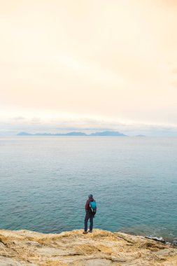 Sırt çantalı kız deniz kıyısındaki bir dağda duruyor. Gezgin, dağda durarak denize bakıyor. Türkiye 'ye gitmek. özgürlük ve mutluluk.