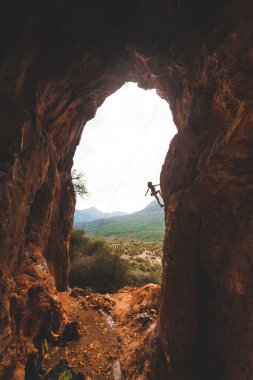 Bir adam bir dağ manzarasına karşı kayaya tırmanır. Sporcu doğal bir rahatlama ile antrenman yapar. Türkiye 'de tırmanış. Kemer şeklinde bir kaya. Mağara. Dağcı zor bir yolun üstesinden gelir..