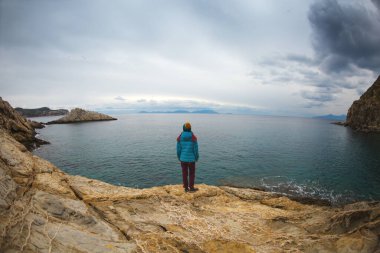 Sırt çantalı kız deniz kıyısındaki bir dağda duruyor. Gezgin, dağda durarak denize bakıyor. Türkiye 'ye gitmek. özgürlük ve mutluluk.
