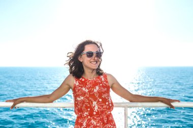 Kırmızı elbiseli mutlu kız gemide yüzüyor. Yaz okyanus gezisi. Yaz tatili.