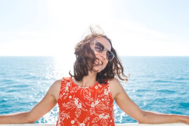 Bir kadın yolcu gemisinde yelken açıyor, bir kız bir gemide çitin yanında duruyor ve denize bakıyor, feribotla seyahat ediyor, yaz elbisesi giymiş bir esmer okyanusa hayran..