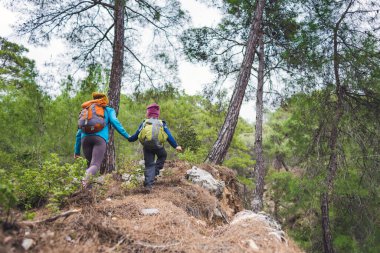 Annesiyle dağlara yürüyüşe çıkmış bir çocuk, sırt çantalı bir çocuk annesiyle ormanda yürüyor, bir kadın çocuğuyla birlikte güzel yerlere seyahat ediyor, aktif tatiller yapıyor..