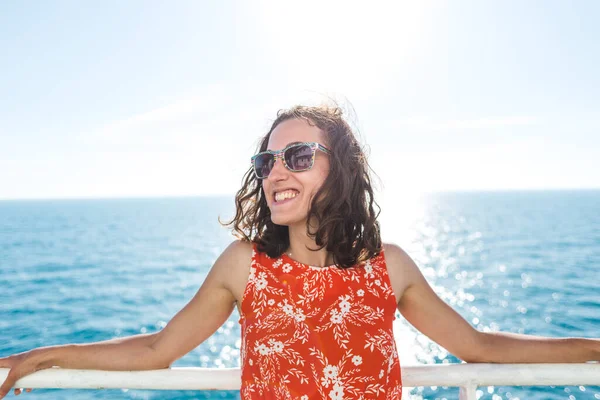 happy girl in a red sundress floats on the ship. summer ocean cruise. summer rest.
