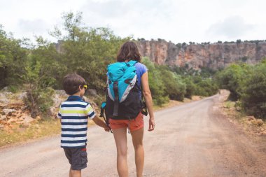 Sıcak mevsimde dağlarda ve ormanlarda yürüyüş. Anne ve çocuk dağlarda yürüyüşe çıktılar. bir çocukla aktif hafta sonu.