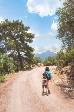 Sıcak mevsimde dağlarda ve ormanlarda yürüyüş. Anne ve çocuk dağlarda yürüyüşe çıktılar. bir çocukla aktif hafta sonu.