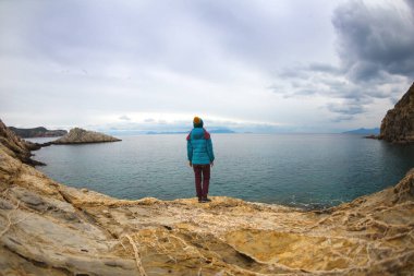 Sırt çantalı kız deniz kıyısındaki bir dağda duruyor. Gezgin, dağda durarak denize bakıyor. Türkiye 'ye gitmek. özgürlük ve mutluluk.