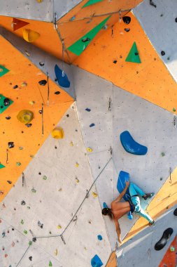 Bir adam tırmanma duvarına tırmanır, bir dağcı yapay arazi eğitimi alır, şehirde kaya tırmanışı yapar, güçlü bir adam, şehirde spor yapar, aşırı sporlarda güvenlidir..