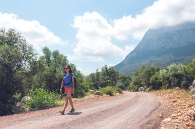 Sırt çantalı bir kız dağ yolunda yürüyor, Türkiye 'yi geziyor, resimli yerlerde geziyor, yürüyüş yapıyor, turistik bir yolda yürüyor, dağ yolunda..