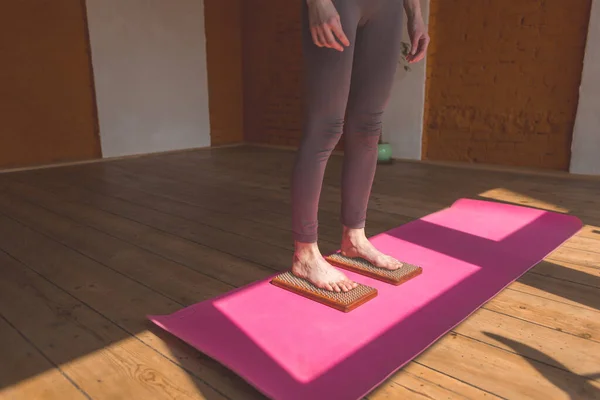 The girl is engaged in yoga and meditation, standing on the sadhu board. wooden board with metal nails. yoga class.