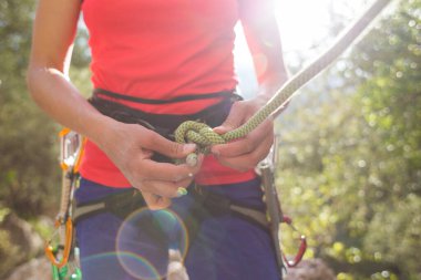 Kaya tırmanışçısı bir kız dağlarda güvenli bir tırmanış yapmak için kendini iple bağlıyor. Sporda güvenlik. Kaya tırmanışı için hazırlık. Sokaklarda spor yapıyor..