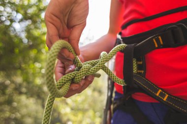 Kaya tırmanışçısı bir kız dağlarda güvenli bir tırmanış yapmak için kendini iple bağlıyor. Sporda güvenlik. Kaya tırmanışı için hazırlık. Sokaklarda spor yapıyor..