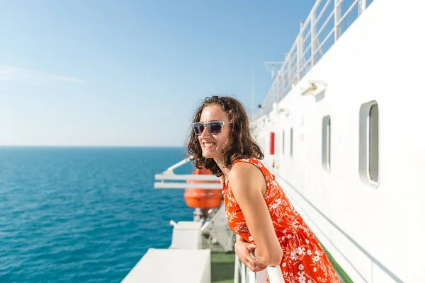 happy girl in a red sundress floats on the ship. summer ocean cruise. summer rest.