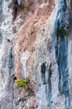 Bir kız ormanın arka planında bir kayaya tırmanır, atlet doğada antrenman yapar, kadın zor tırmanış rotasının üstesinden gelir, güçlü dağcı, aşırı hobi, Türkiye 'de kaya tırmanışı.