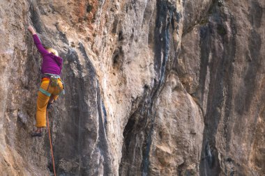 Bir kız kayalar üzerinde güç ve dayanıklılık eğitimi alır, doğal araziye tırmanır, bir kaya tırmanıcısı zor bir rotanın üstesinden gelir, aktif bir yaşam tarzı. kaya tırmanışı