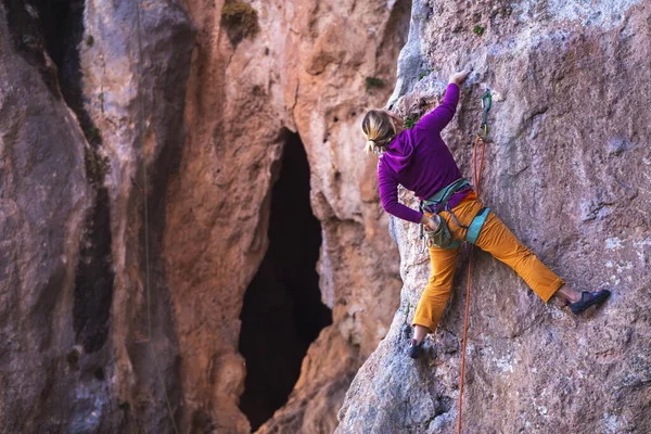 Bir kız kayalar üzerinde güç ve dayanıklılık eğitimi alır, doğal araziye tırmanır, bir kaya tırmanıcısı zor bir rotanın üstesinden gelir, aktif bir yaşam tarzı. kaya tırmanışı