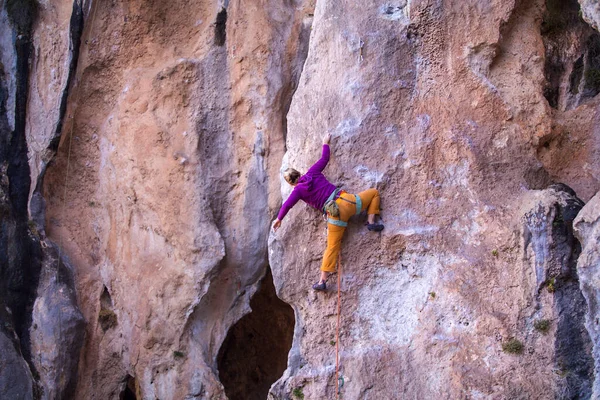 Bir kız kayalar üzerinde güç ve dayanıklılık eğitimi alır, doğal araziye tırmanır, bir kaya tırmanıcısı zor bir rotanın üstesinden gelir, aktif bir yaşam tarzı. kaya tırmanışı