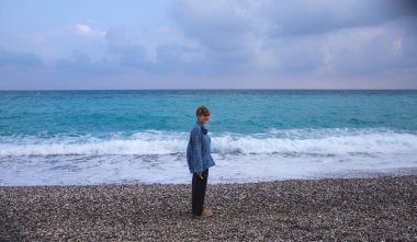 Sahilde yürürken mutlu kaygısız kadın. Deniz kenarında güneşli bir gün. Mutlu yaşam tarzı konsepti. Elbiseli bir kız deniz kıyısında yürüyor..