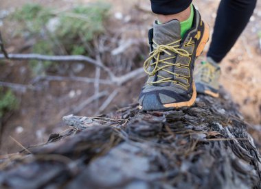 Kız engelli bir yarışa katılıyor, ormanda engelli bir yarışa katılıyor, kadın bacakları yakın planda, kadın bacakları bir kütükte koşuyor, engellerle koşuyor.
