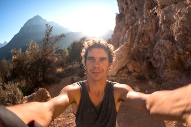 Bir adam güzel bir dağ vadisinin ve kayaların arka planında selfie çeker, Türkiye 'de resim gibi yerlerde seyahat eder, Türkiye Kayaları, Kaya tırmanışı.