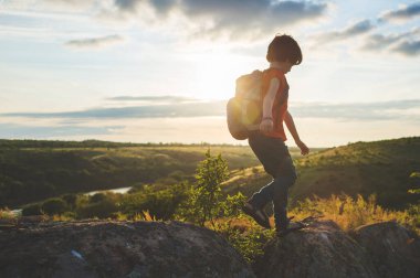 Yürüyüşe çıkmış sırt çantalı bir çocuk. Bir çocukla yürüyüşe çıkmak. Doğada yaz tatili.