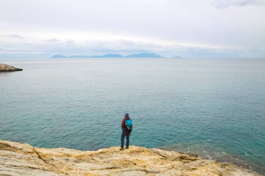 Sırt çantalı kız deniz kıyısındaki bir dağda duruyor. Gezgin, dağda durarak denize bakıyor. Türkiye 'ye gitmek. özgürlük ve mutluluk.