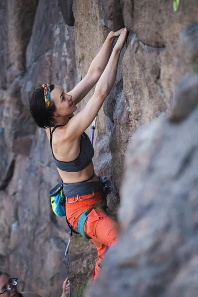少女は岩の上をロッククライミングしようとします 女子登山家は困難な道を登り — ストック写真