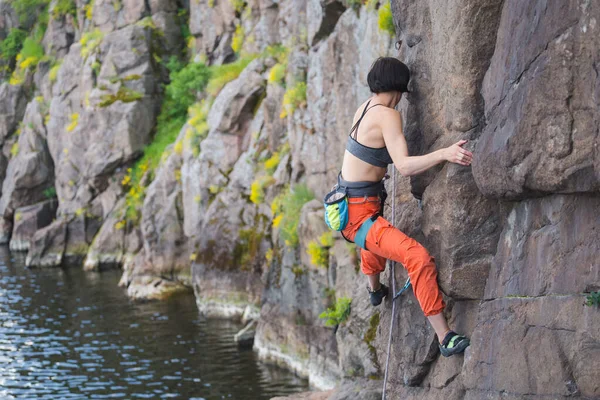 少女は水中で岩登りに従事しています 岩登りは難しいルートを克服します 自然界のスポーツやフィットネスは — ストック写真