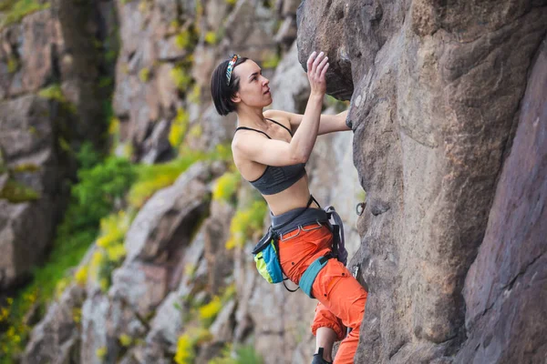 少女は岩の上をロッククライミングしようとします 女子登山家は困難な道を登り — ストック写真