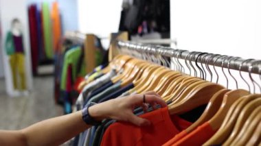 Bir mağazada bir kız, bir kadın mağazada bir tişört seçer, satış, yeni bir koleksiyon, bir kadın bir erkeğe hediye alır.