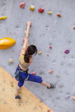 Gülümseyen kız tırmanma duvarına tırmanıyor, kadın ekstrem sporlarla meşgul, şehirde kaya tırmanışı, güç ve dayanıklılık eğitimi alıyor.