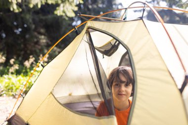 Bir çocuk çadırdan dışarı bakar, bir çocuk portresi, ailesiyle seyahat eden bir çocuk, ormanda piknik, çocuklarla dağlarda yürüyüş