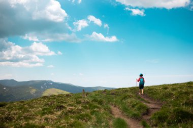 Bir çocukla dağlarda yürümek, sırt çantalı bir çocuk dağ yolunda yürümek, çocuklar için açık hava eğlencesi..