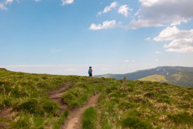 Bir çocukla dağlarda yürümek, sırt çantalı bir çocuk dağ yolunda yürümek, çocuklar için açık hava eğlencesi..