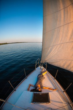 bir yatla seyahat etmek. Kız gemide dinleniyor. Beyaz bir yatın güvertesinde dinleniyor..