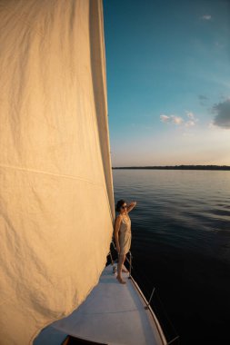 bir yatla seyahat etmek. Kız geminin pruvasında duruyor ve uzaklığa bakıyor. Beyaz bir yatın güvertesinde dinleniyor..