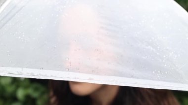 Şemsiye altında gülümseyen kız, yaz yağmurunda şeffaf şemsiye altında makyajsız kadın.