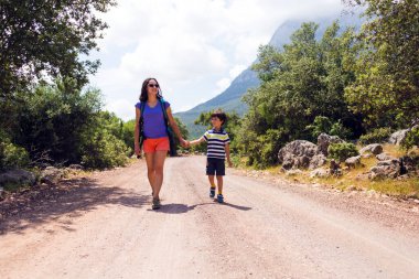 Annesiyle dağların arka planında gezen bir çocuğun portresi, bir kadın çocuğuyla seyahat eder, bir sırt çantalı kız bir çocukla yürüyüşe çıkar, çocuklarla seyahat eder.