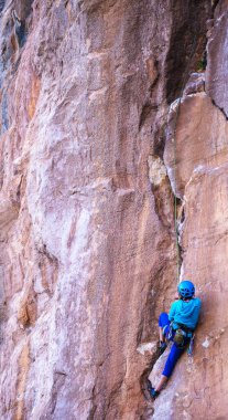 Kasklı bir kadın güzel mavi bir kayaya tırmanır. Koruyucu ekipmana tırmanıyorum. Tırmanırken güvenlik. Kaya tırmanışçısı doğal bir arazide zorlu bir rotanın üstesinden gelir. Türkiye 'de kaya tırmanışı.