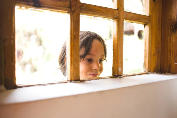 Ciekawy Chłopiec Wygląda Przez Okno Dziecko Podgląda Dom Przez Okno — Zdjęcie stockowe