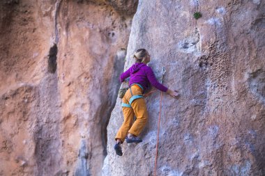 Bir kız kayalar üzerinde güç ve dayanıklılık eğitimi alır, doğal araziye tırmanır, bir kaya tırmanıcısı zor bir rotanın üstesinden gelir, aktif bir yaşam tarzı. kaya tırmanışı