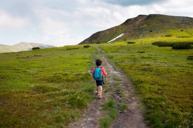 Sırt çantalı çocuk dağ yolunda yürüyor. Doğada dinlenmek. Çocuk kampı