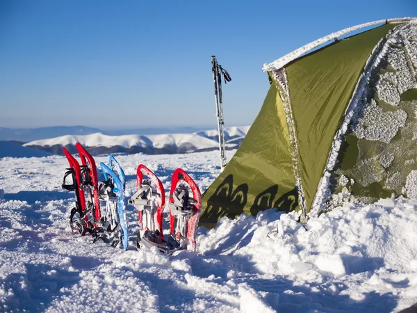 Sapatilhas de neve e tenda nas montanhas . — Fotografia de Stock