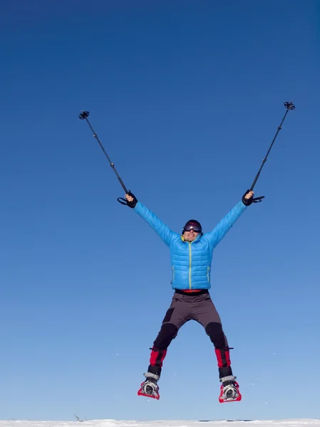 El hombre en raquetas de nieve salta en las montañas . — Foto de Stock
